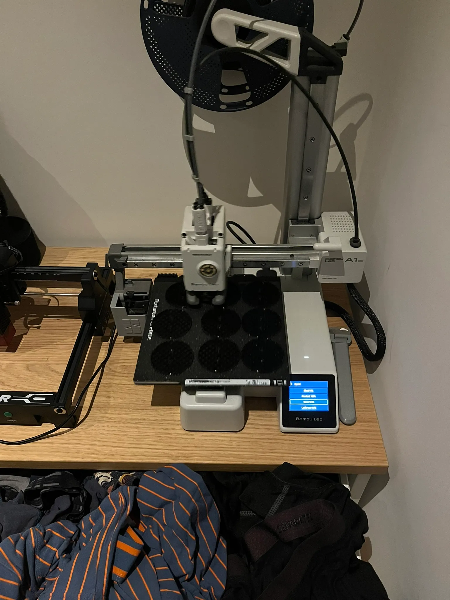 A 3D printer on a shelf, printing a batch of round nodes.